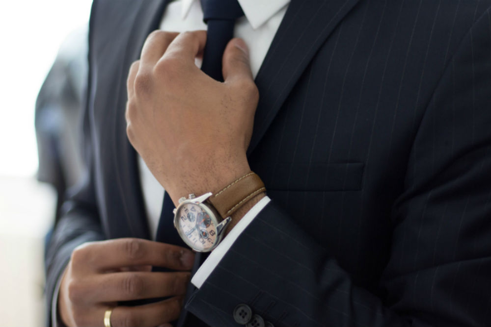 Man wearing suit tightens tie before work